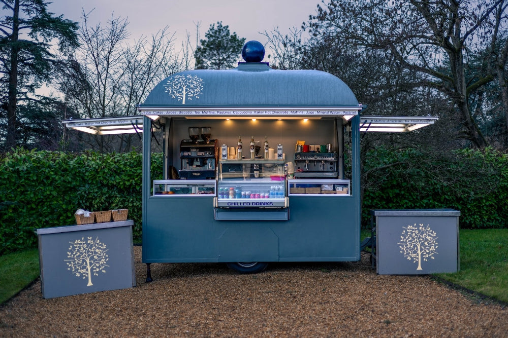 Blue food cart with tree design in a garden setting