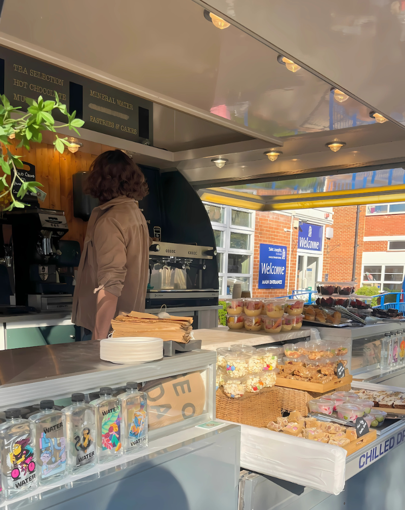 Person standing at a food counter with various food items displayed.